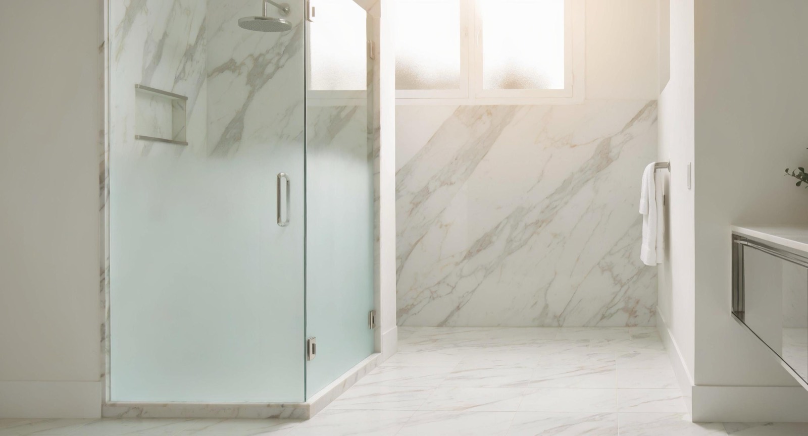 Frameless frosted shower enclosure in a marble bathroom